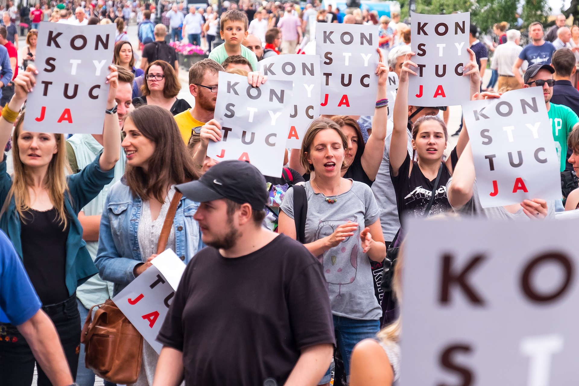 Multitud de mujeres, al frente un hombre, con carteles en marcha.
