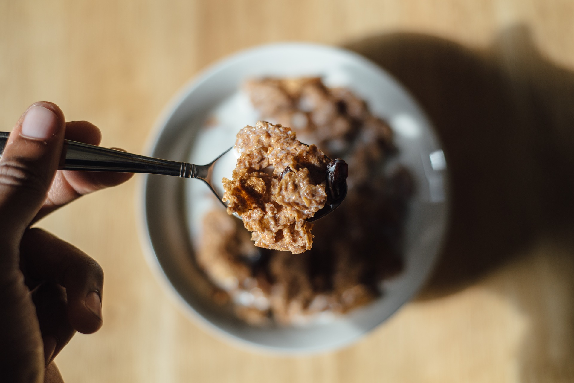 labor_t1 plato de cereal y mano con cuchara llena de cereal.