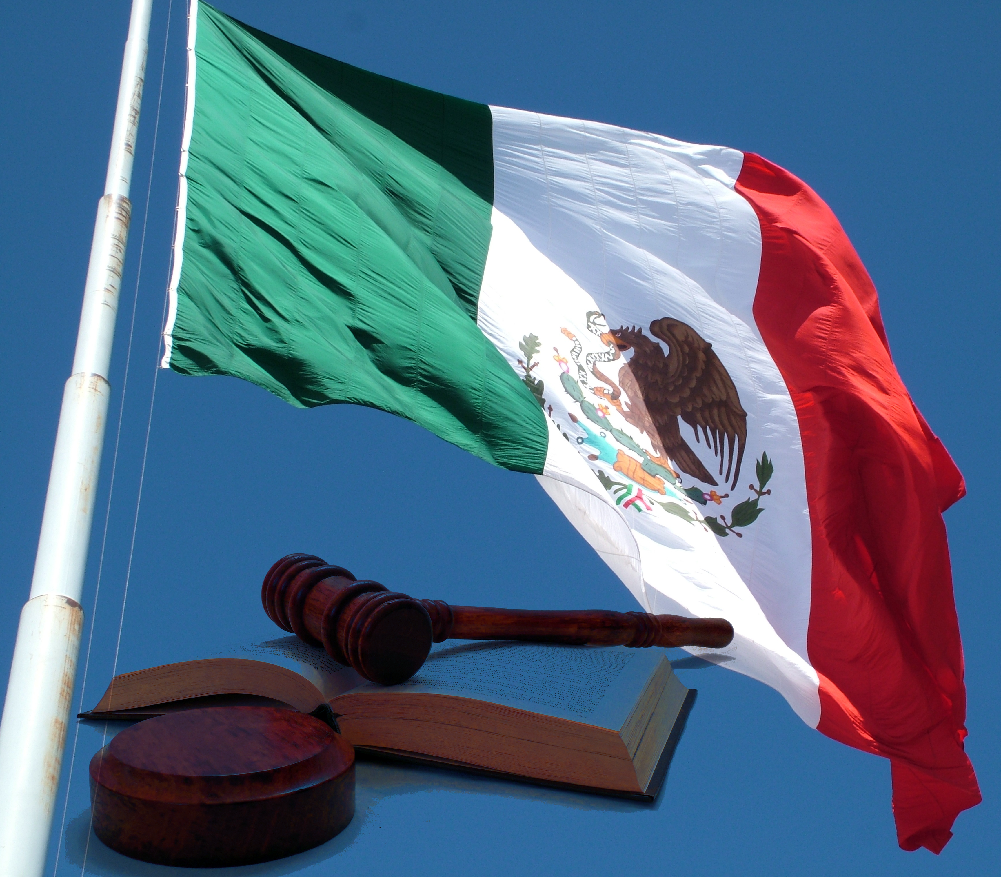 Bandera de México con un libro y un mazo al lado.