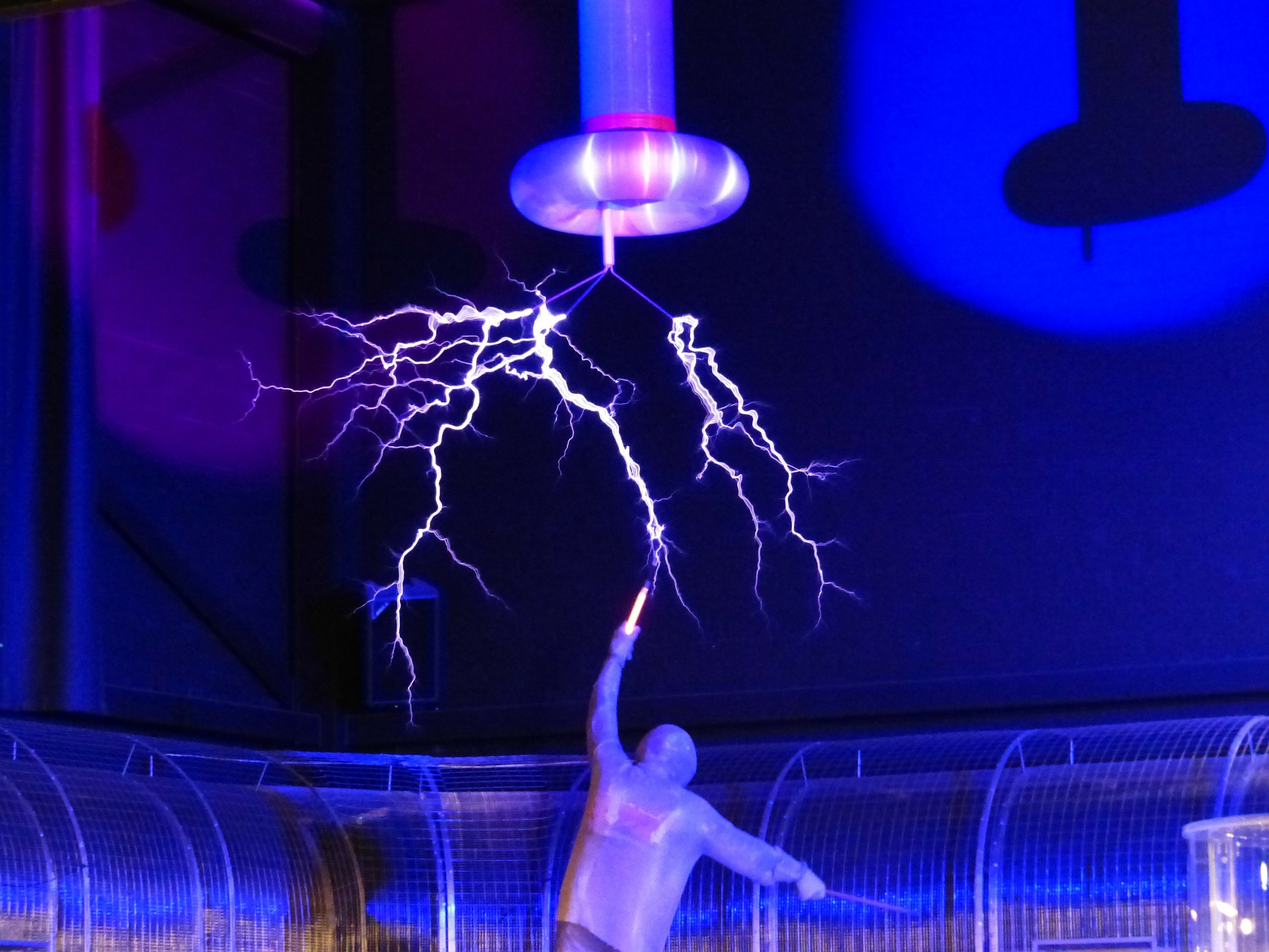 Silueta humana que extiende brazo hacia arriba para incidir en trayectoria de rayos eléctricos.