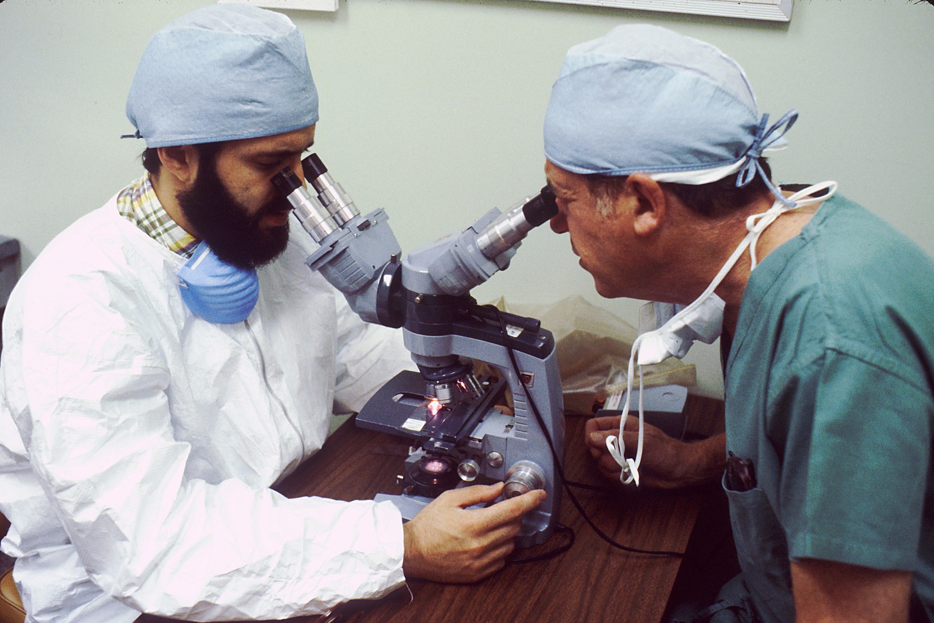 dos hombres observan muestra en un solo microscopio.